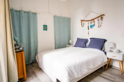 a bedroom with a white bed and blue curtains at Appartement très cosy avec cour in Cannes
