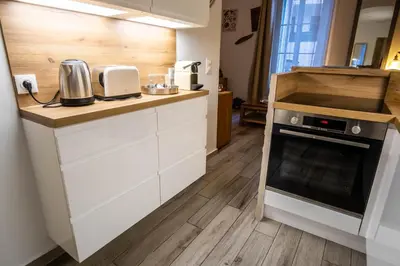 a kitchen with white cabinets and a wooden counter top at Appartement très cosy avec cour in Cannes