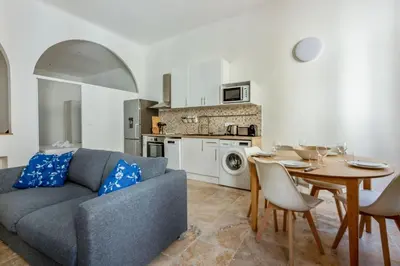 a living room with a couch and a table with chairs at Appartement Immaculia - Welkeys in Cannes