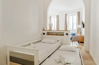 a white bedroom with a bed and a table at Appartement Immaculia - Welkeys in Cannes