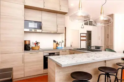 a kitchen with wooden cabinets and a counter with stools at Luxury 3 Bd Aptment with Sea view in Cannes