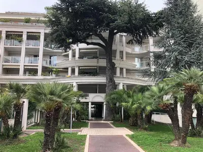 a large white building with palm trees in front of it at CAM0 - appartement 2 chambres en rez-de-terrasse in Cannes