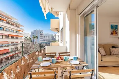 a table on a balcony with a view of a city at Le Vautrin - Charmant Appartement à 300 mètres des plages de la Croisette in Cannes