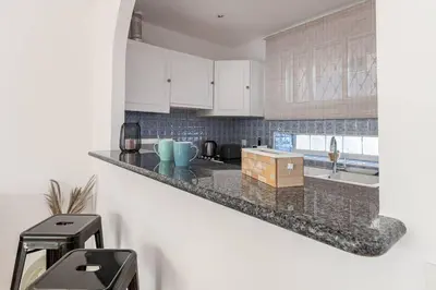 a kitchen with white cabinets and a counter top at Le Vautrin - Charmant Appartement à 300 mètres des plages de la Croisette in Cannes
