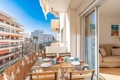 a table on a balcony with a view of the city at Le Vautrin - Charmant Appartement à 300 mètres des plages de la Croisette in Cannes