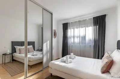 a white bedroom with a mirror and a bed at Le Vautrin - Charmant Appartement à 300 mètres des plages de la Croisette in Cannes