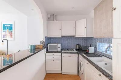 a kitchen with white cabinets and a stove top oven at Le Vautrin - Charmant Appartement à 300 mètres des plages de la Croisette in Cannes