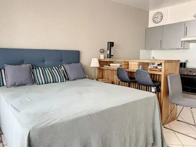 a bedroom with a large bed and a kitchen at Cannes - Studio en plein cœur de Cannes in Cannes
