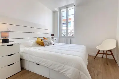 a white bedroom with a white bed and a chair at HENRI CAMILLE REAL ESTATE - Bambou- One bedroom apt downtown in Cannes