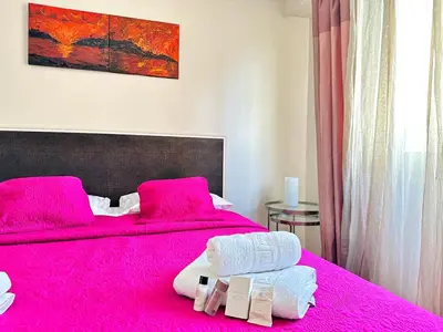 a bedroom with a pink bed with towels on it at L'Azur - Appartement 2 chambres - Terrasse in Cannes