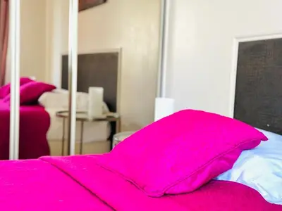 a bed with a pink blanket on top of it at L'Azur - Appartement 2 chambres - Terrasse in Cannes
