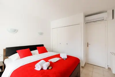 a bedroom with a red and white bed with towels on it at Les Liserons YourHostHelper in Cannes