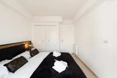 a bedroom with a bed with white sheets and pillows at Les Liserons YourHostHelper in Cannes