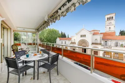 a balcony with a table and chairs and a view of a building at Les Liserons YourHostHelper in Cannes