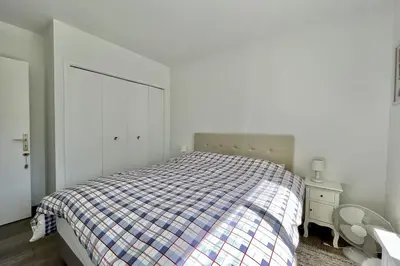 a bed in a white room with a plaid blanket at Beautiful flat with terrace near Croisette in Cannes