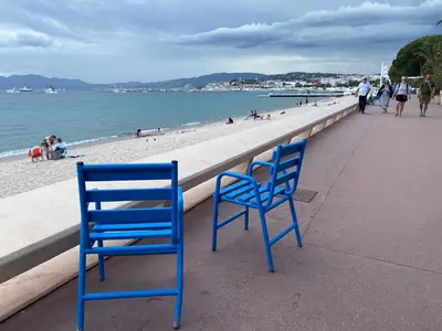two blue chairs sitting on a sidewalk near the beach at Studio CANNES PARC CROISETTE in Cannes