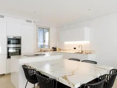 a white kitchen with a marble table and chairs at Appartement Avec Terrasse Centre-ville Croisette in Cannes