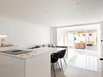 a white kitchen with a large island with black chairs at Appartement Avec Terrasse Centre-ville Croisette in Cannes