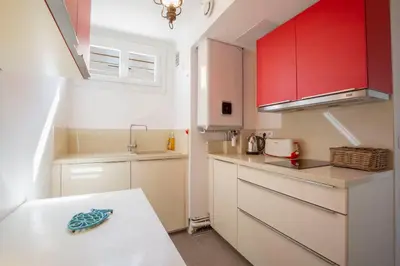 a small kitchen with red cabinets and a table at WE CANNES ! Cosy 2-bedroom apartment with terrace Cannes Center in Cannes