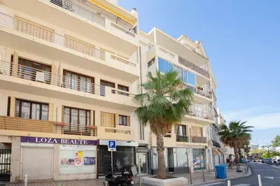 a building with a palm tree in front of a street at WE CANNES ! Cosy 2-bedroom apartment with terrace Cannes Center in Cannes