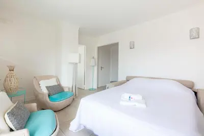 a white bedroom with a bed and a chair at WE CANNES ! Cosy 2-bedroom apartment with terrace Cannes Center in Cannes