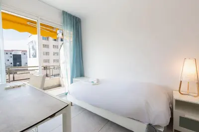 a white bedroom with a bed and a large window at WE CANNES ! Cosy 2-bedroom apartment with terrace Cannes Center in Cannes