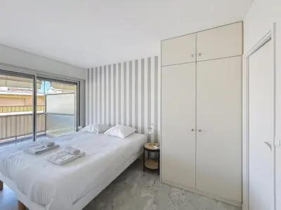 a bedroom with a white bed and a large window at Appartement Canto bright appartement Croisette beach in Cannes