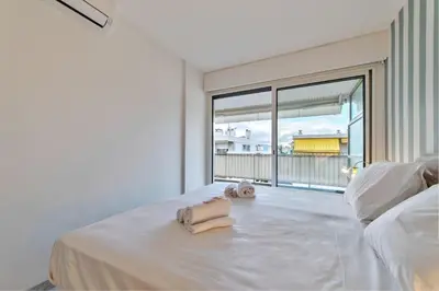 a white bedroom with a bed with a large window at Appartement Canto bright appartement Croisette beach in Cannes