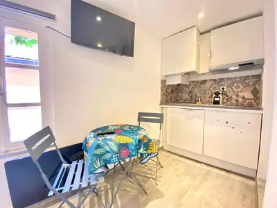 a kitchen with white cabinets and a table and chairs at Mini Studio - Le Panisse By SCLS Locations in Cannes