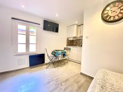 a room with a clock on the wall and a kitchen at Mini Studio - Le Panisse By SCLS Locations in Cannes