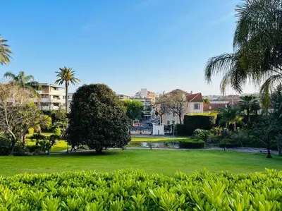 a park with a pond and a tree and buildings at Cannes Montfleury grand confort in Cannes