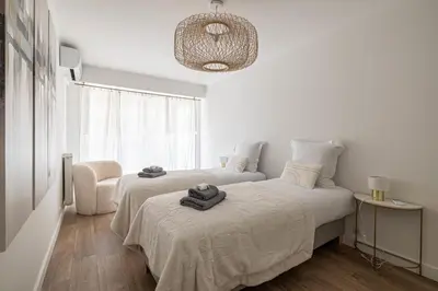 a white bedroom with two beds and a chair at Magnificent 3room apartment quiet balcony in Cannes