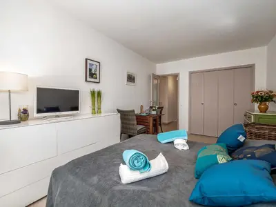 a bedroom with a bed with blue pillows and a television at Apartment Les Sablons-2 by Interhome in Cannes