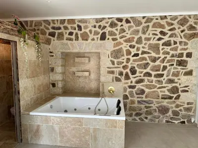 a bath tub in a bathroom with a stone wall at Villa Paradis - Cannes in Cannes