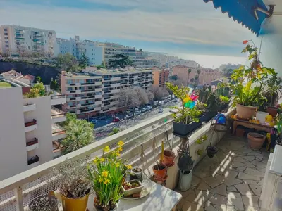 a balcony with potted plants and a view of a city at Le Vallombrosa - Deux pièces lumineux et confortable in Cannes