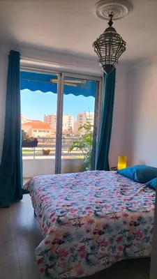 a bedroom with a bed and a large window at Le Vallombrosa - Deux pièces lumineux et confortable in Cannes