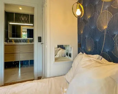 a bedroom with a bed and a wall with a mirror at Piscine privée, Plages à pied & Palais à proximité in Cannes