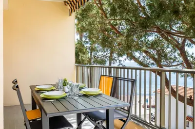 a wooden table with chairs on a balcony at 2-Room Apartment with Terrace Sea View in Cannes