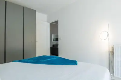 a bedroom with a white bed with a blue blanket on it at 2-Room Apartment with Terrace Sea View in Cannes