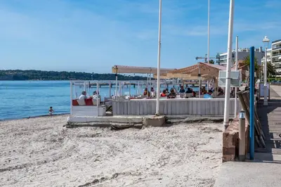 a beach with a bar with people sitting on it at 2-Room Apartment with Terrace Sea View in Cannes