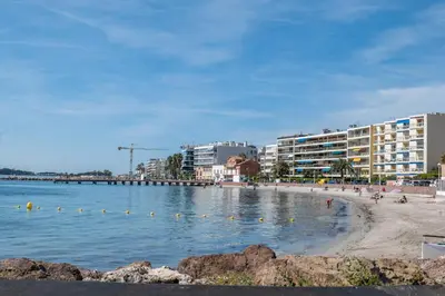 a beach with buildings and people in the water at 2-Room Apartment with Terrace Sea View in Cannes