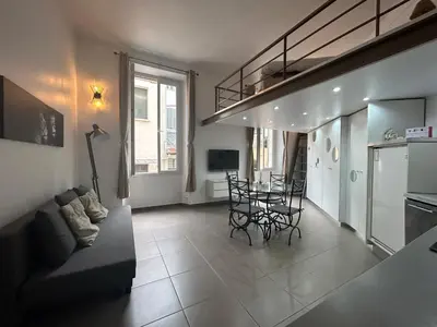 a living room with a couch and a table with chairs at Charmant studio centre ville Cannes in Cannes