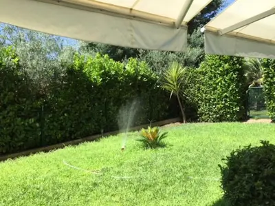 a garden with a sprinkler in the grass at Appartement Les Eucalyptus dans domaine privé à Cannes in Cannes