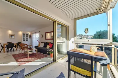 a living room with a large window and a couch at Appartement Reina Pointe Croisette Palm Beach in Cannes