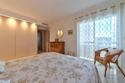 a bedroom with a bed and a chair and a window at Appartement Reina Pointe Croisette Palm Beach in Cannes