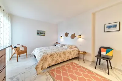 a bedroom with a bed and a chair at Appartement Reina Pointe Croisette Palm Beach in Cannes