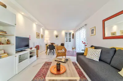 a living room with a couch and a tv at Appartement Reina Pointe Croisette Palm Beach in Cannes