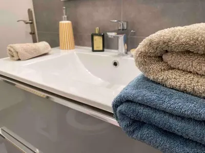 a bathroom with a sink and towels on a counter at L'Orangeraie Centre Cannes Martinez, Beau F2 avec terrasse in Cannes