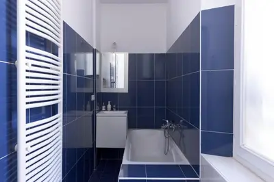 a blue tiled bathroom with a tub and a sink at Carnot Prestige – Spacious & Central in Cannes
