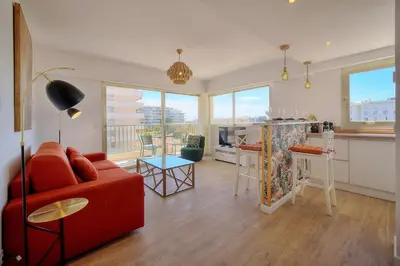 a living room with a red couch and a kitchen at IMMOGROOM - 5 min from the Croisette beaches - Terrace - Ac - Sea view in Cannes